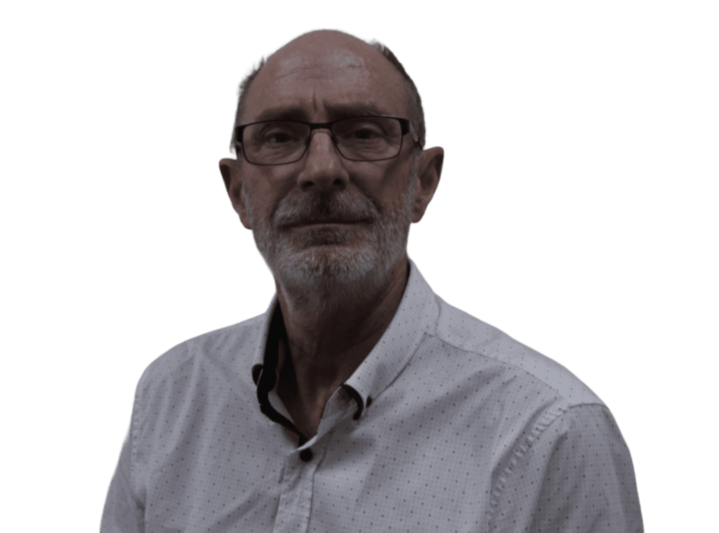 A bald man with glasses and a beard is wearing a white button-up shirt with a dark collar. He is looking straight ahead. The background is solid black.